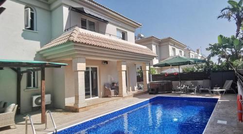 uma casa com piscina em frente a uma casa em GREAT VILLA MARIA em Paralimni
