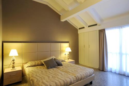 a bedroom with a bed with two lamps and a window at Residence Oliveto in Ceriale