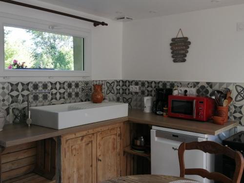 a kitchen with a white sink and a red microwave at Martine à la Ferme in Arrest