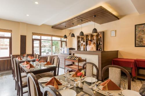 a restaurant with tables and chairs and a man in the kitchen at Hotel Thamel in Kathmandu