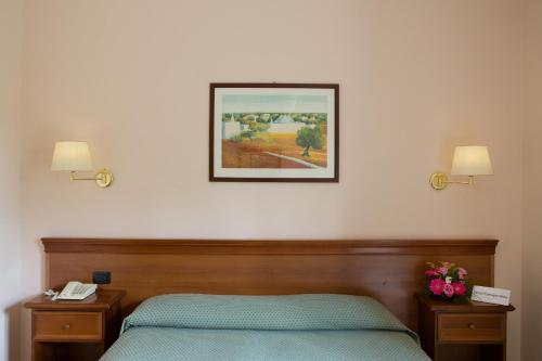 a bedroom with a bed and a picture on the wall at Hotel Ramapendula in Alberobello