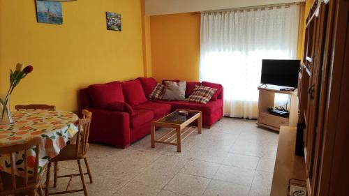 - un salon avec un canapé rouge et une table dans l'établissement Amplio piso en Pontedeume, à Pontedeume