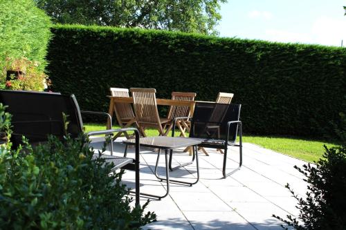 een patio met stoelen, een tafel en een heg bij Le mélèze heureux 