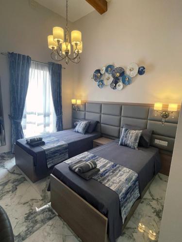a bedroom with two beds and a chandelier at Ta' Dun Martin and taz-Zija Bed and Breakfast in Nadur