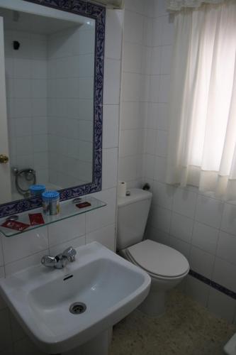 a bathroom with a toilet and a sink and a mirror at Pensión Campomar in Cartaya