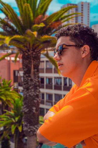 a man in an orange shirt standing in front of a palm tree at Hotel Tropical in Puerto de la Cruz