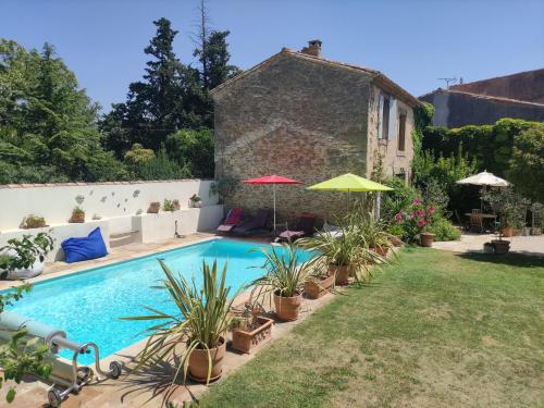 une piscine avec des plantes et des parasols dans une cour dans l'établissement The Cottage, Clos des Archers, à Aigues-Vives