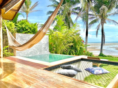 a hammock and a pool on a patio with the beach at Nibbana Bungalows in Hinkong