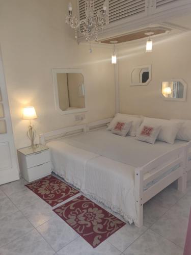a white bedroom with a large white bed with a red rug at Kristu re in Fgura