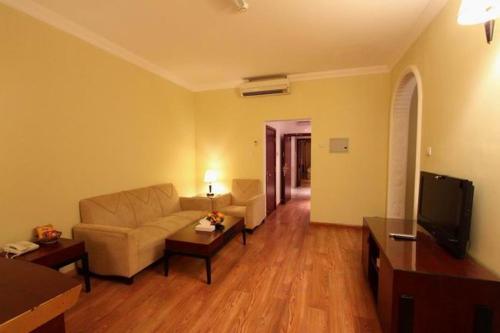 a living room with a couch and a tv at Al Maha Residence Rak in Ras al Khaimah