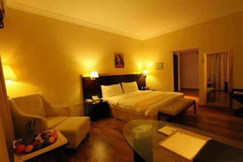 a hotel room with a bed and a living room at Al Maha Residence Rak in Ras al Khaimah