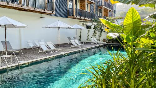 a pool with chairs and umbrellas next to a building at Résidence Santa Apolonia in Saint-Leu