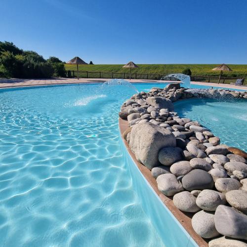 a swimming pool with rocks in the water at La Forêt Enchantée in Cornille
