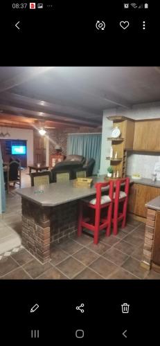 cocina con mesa y 2 sillas rojas en House Ebenezer en Bloemfontein