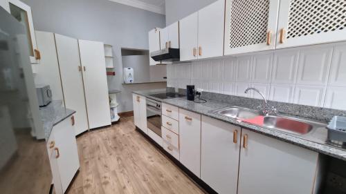 eine Küche mit weißen Schränken und einer Spüle in der Unterkunft Everly4 Guest Apartment in Durban