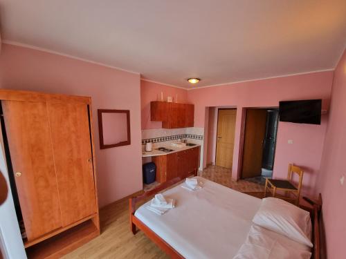 a bedroom with a white bed and a kitchen at BetaNovalja in Novalja