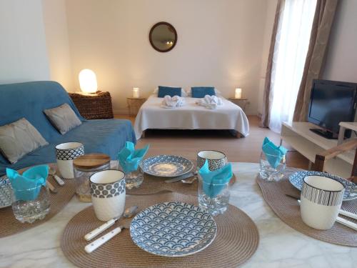 a living room with a couch and a table with dishes at La Guest House BYLAVILLA25 calme et détente in Noaillan