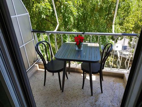 una mesa azul con un jarrón de flores en el balcón en Zeus Apartment, en Atenas