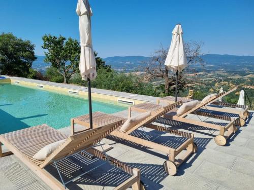 a row of lounge chairs with umbrellas next to a swimming pool at Agriturismo I Millepini in Case Malva