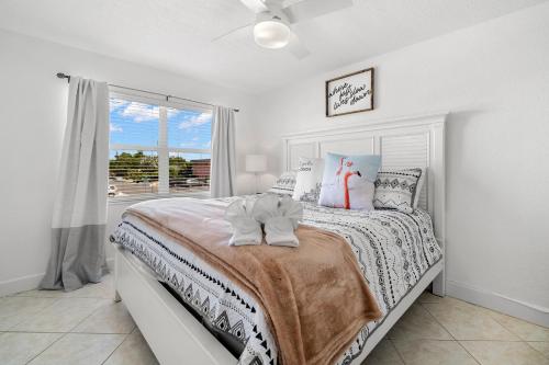 a white bedroom with a bed and a window at Waves 17, 1 Bedroom, Sleeps 4, Pool View, Heated Pool, BBQ, WiFi in St Pete Beach
