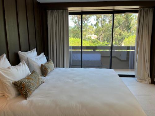 a large white bed in a room with a large window at Hôtel Spa & Restaurant - Son de Mar in Porto-Vecchio