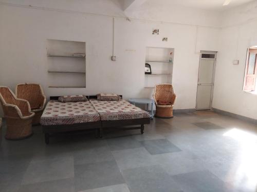 1 dormitorio con 1 cama y sillas en una habitación en JAWAI WILD LODGE, en Bijāpur