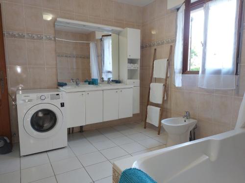a bathroom with a washing machine and a sink at La Guest House BYLAVILLA25 calme et détente in Noaillan
