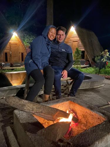a man and woman sitting on a bench next to a fire at Triangle House and hot spring in Kintamani