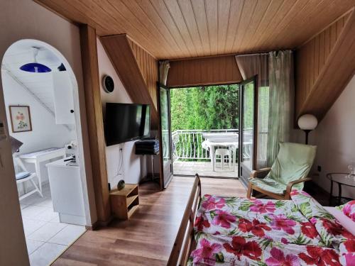 a bedroom with a bed and a balcony with a table at Kaméleon Apartmanház EV töltéssel in Balatonszemes