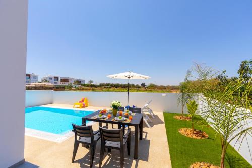 a patio with a table and chairs next to a swimming pool at Alasia Villas in Paralimni