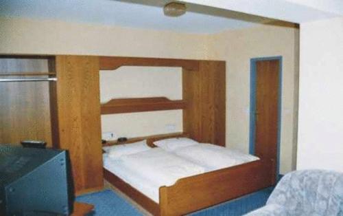a bed with a wooden frame in a room with a tv at Hotel Ludwigstal in Schriesheim