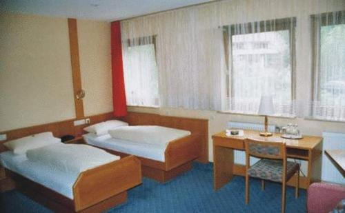Habitación con 2 camas, mesa y escritorio. en Hotel Ludwigstal en Schriesheim