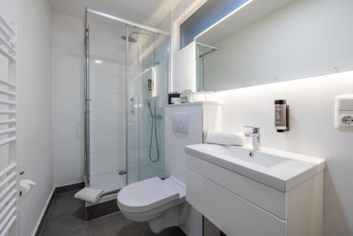 a white bathroom with a sink and a shower at Hotel KO15 in Lübeck
