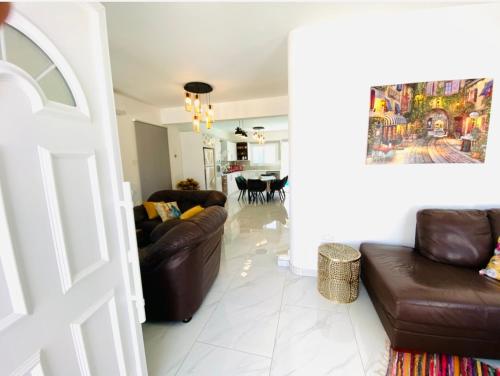 a living room with two brown leather couches and a kitchen at Exclusive Villa Larnaca - 8 plus sleeps - 2 min from BEACH - Big Private Pool in Pyla