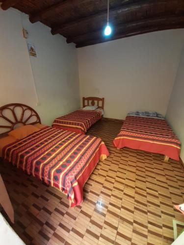 two beds sitting in a room with wooden floors at Mama Chelita in Nazca