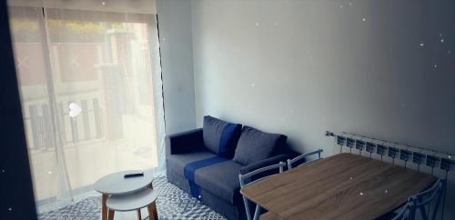 uma sala de estar com um sofá azul e uma mesa em Studio aux portes d' Amiens em Cagny