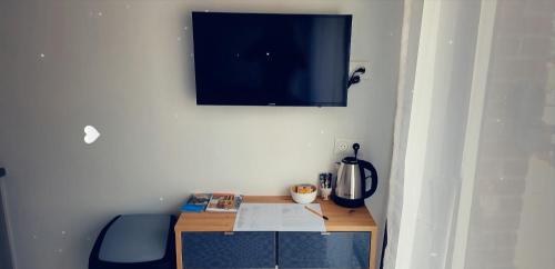 uma pequena secretária com uma televisão na parede em Studio aux portes d' Amiens em Cagny