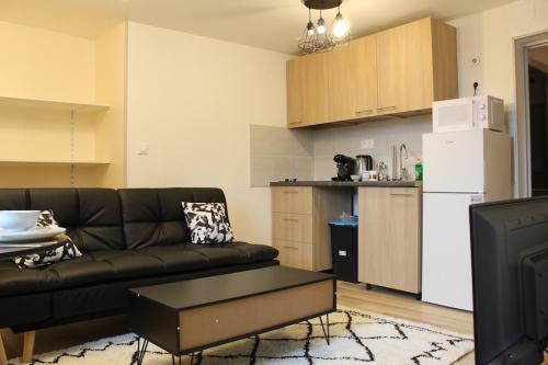 a living room with a couch and a kitchen at LES COTTAGES DU PRYTANEE in La Flèche