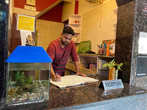 a man standing behind a counter with a fish tank at Friends Guest House & Hostel- near TAJ MAHAL in Agra