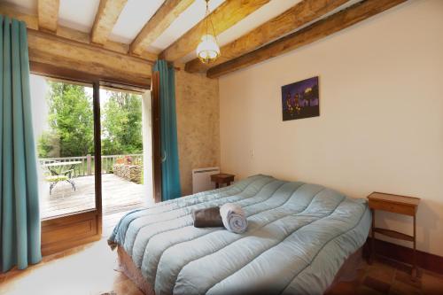 a bedroom with a large bed and a balcony at Studio campagne in Mézeray