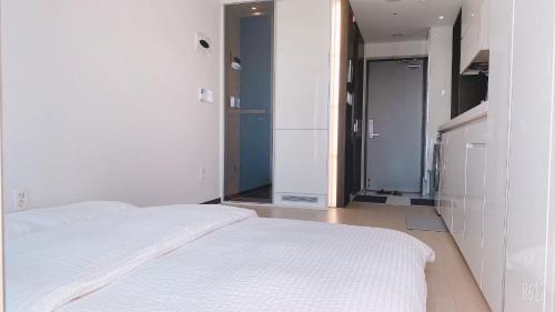 a white bedroom with two beds and a mirror at Shine Hotel Incheon Airport in Incheon