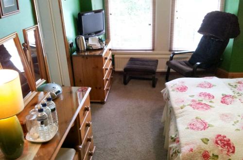 a bedroom with a bed and a dresser and a television at COLLEGE HOUSE in Windermere