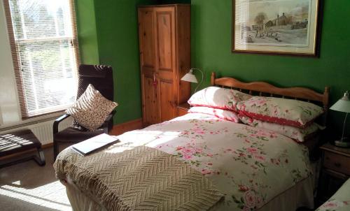 a green bedroom with a bed and a chair at COLLEGE HOUSE in Windermere