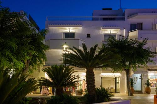 a white building with palm trees in front of it at IROCO HOSTAL in Cala d´Or