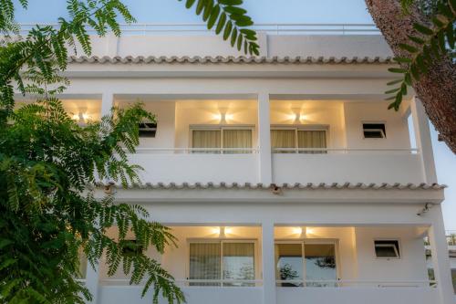 un edificio de apartamentos blanco con balcón blanco en IROCO HOSTAL, en Cala d´Or