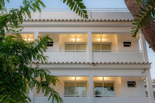 un edificio de apartamentos blanco con balcón blanco en IROCO HOSTAL en Cala D'Or