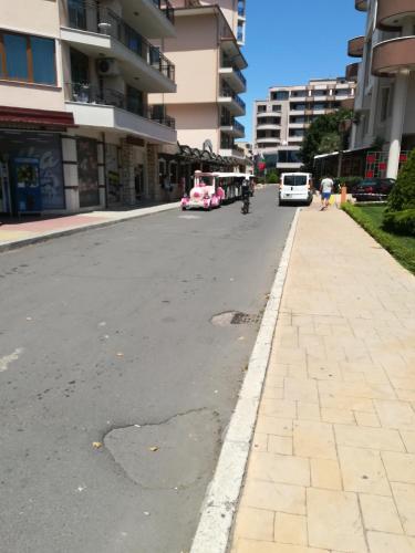 een lege stadsstraat met auto's en gebouwen bij Apartment Orhideya in Sunny Beach