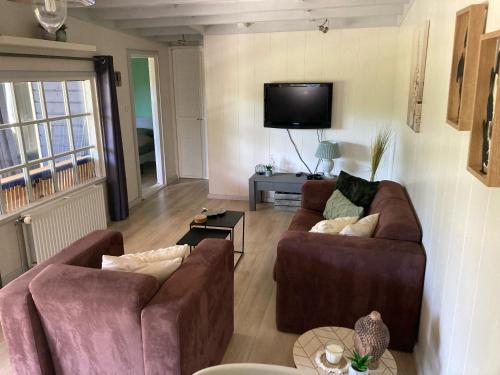 uma sala de estar com 2 sofás e uma televisão de ecrã plano em De Weide Blick em Biggekerke