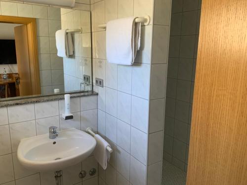 La salle de bains blanche est pourvue d'un lavabo et d'un miroir. dans l'établissement Gasthaus Sonne, à Hohenstadt