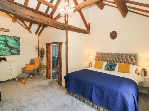 a bedroom with a large bed and a chair at Tulip Cottage in Shipley